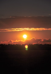 Orange sun sets in beautiful cumulus clouds. iIdyllic countryside landscape