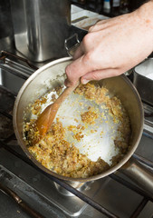 Turmeric powder being mixed into a pan of frying minced garlic and finely sliced onion. Step by step recipe cooking.