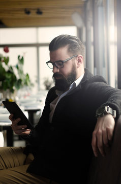 hipster man or a man with a beard using tablet in the coffee sho