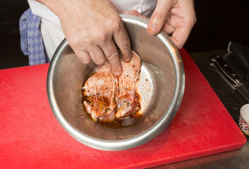An organic, free range raw duck fillet, being marinated in a metal mixing bowl.