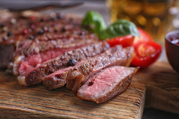 Grilled steak with tomatoes on cutting board, closeup