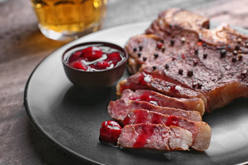 Grilled steak on plate and mug of beer on wooden background