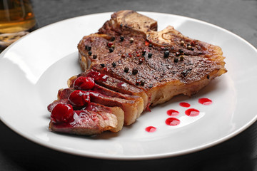 Grilled steak with drops of sauce on plate, closeup