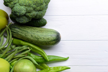 Green vegetables and fruits on wooden background