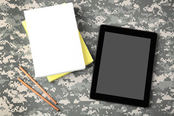 Tablet and copybooks on camouflage background