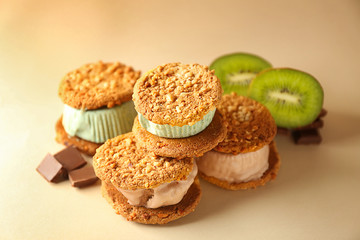 Fototapeta na wymiar Delicious ice cream cookie sandwiches with kiwi and chocolate on beige background