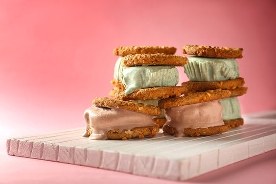 Delicious kiwi and chocolate ice cream cookie sandwiches on white wooden board and pink background