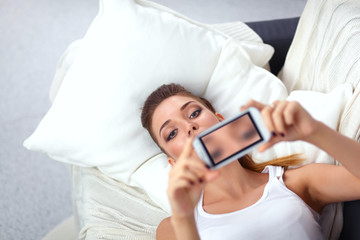 Happy brunette taking a photo of herself with her mobile phone in bedroom