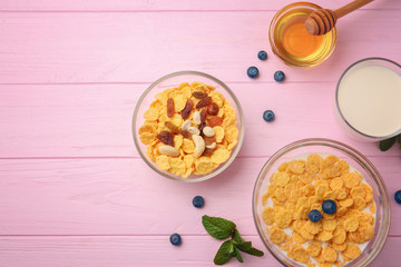 Tasty cornflakes with blueberries,nuts and raisins on pink background