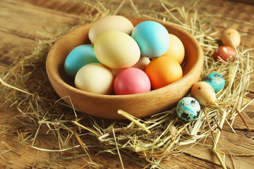 Fototapeta na wymiar Bowl with colorful Easter eggs on wooden table