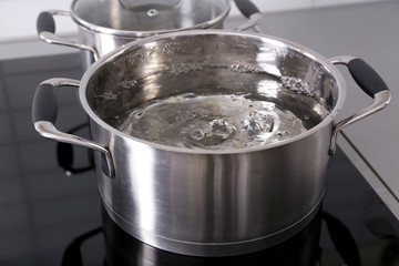 Metal pan with boiling water on modern kitchen stove