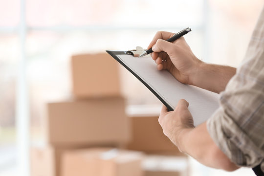Man holding clipboard on blurred boxes background