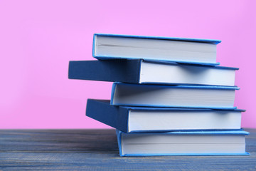 Books on wooden table and pink background