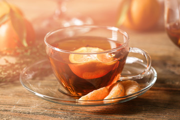 Cup of tangerine tea on wooden background