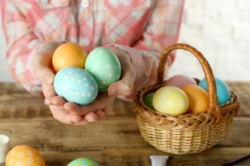Woman holding Easter eggs at wooden table