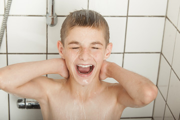 Happy male teenager alone in shower stall