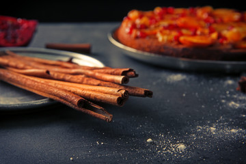 Cinnamon sticks on tray with delicious tangerine pie on background