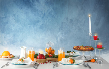 Table setting with candles and fruits on color background