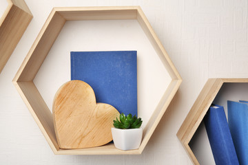 Different books on wooden shelves against light wall