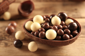 Chocolate Easter egg and candies on wooden background