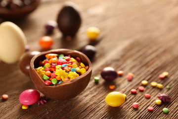 Chocolate Easter eggs and colorful candies on wooden background