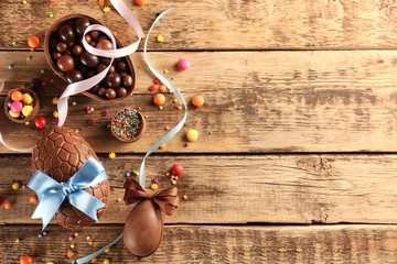 Chocolate Easter eggs with color ribbon bows on wooden background