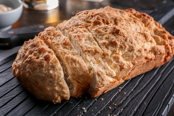 Board with tasty loaf of beer bread on table
