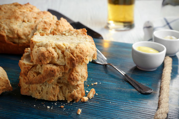 Board with tasty loaf of beer bread on wooden table