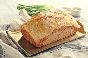 Copper tray with tasty loaf of beer bread on wooden table