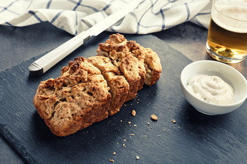 Slate plate with tasty loaf of beer bread on table