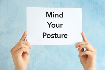 Hands holding paper with phrase MIND YOUR POSTURE on light background