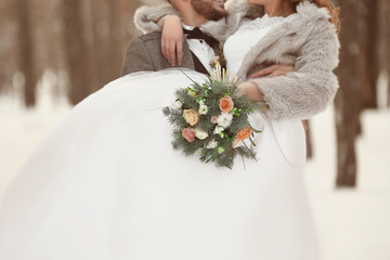 Happy wedding couple with bouquet outdoors on winter day