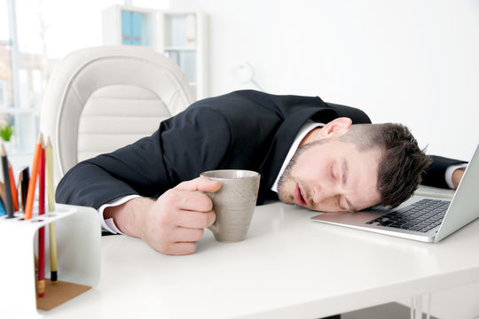 Young business man sleeping on table at workplace