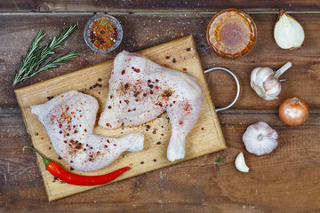 Top view, raw chicken leg with spices on a cutting board, rural style
