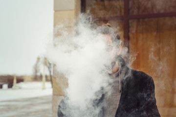 The man in the smoke. He smokes electronic cigarette. Evaporate.