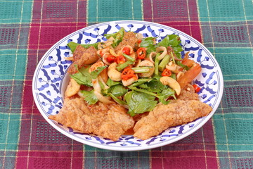Spicy and sour mixed herb salad with crispy pork served .