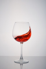 glass red wine splashing on a white background