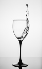 Water splashing in wine glass on white background