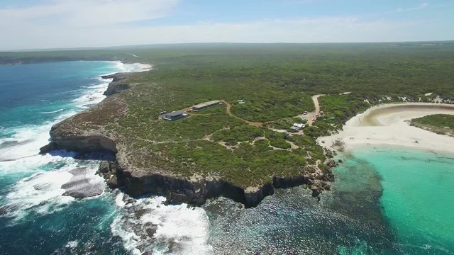 Slow descend over rugged ocean coastline with breaking waves on bright sunny day.  Kangaroo Island, South Australia