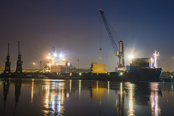 Fototapeta premium unloading cargo ship with containers in sea port at night