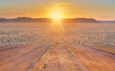 wood board table in front of field of wheat on sunset light.