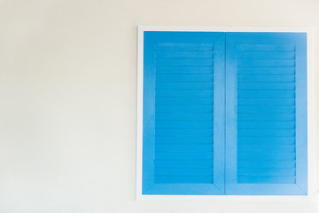 Blue shutters window on a white wall. in the wall of the house.