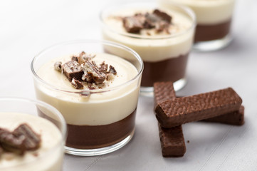 No-bake layered chocolate mousse and cheesecake with chocolate covered wafer cookie crumbs topping. In clear glass dessert bowls. On white background. Great recipe, creamy, light and not too sweet!