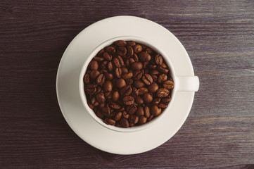 Cup with coffee beans on dark wooden background