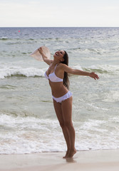 Happy young woman standing on beach and laughing