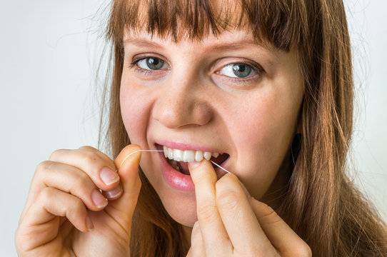 Woman cleaning teeth with dental floss