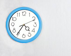 Blue wall clock hanging on white wall