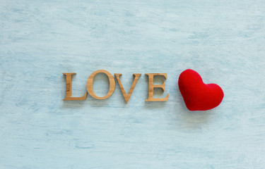 Wooden love text and red heart over blue texture background
