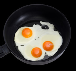 Three fried eggs on the frying pan during cooking closeup