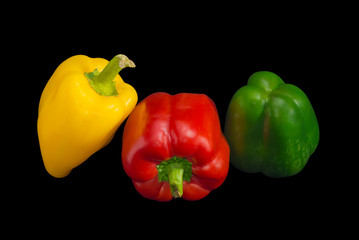 Yellow, red and green bell peppers on a dark background